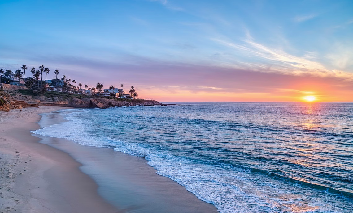 breathtaking sunset over a sandy san diego beach with palm tree silhouettes ocean waves and vivid pink and orange sky