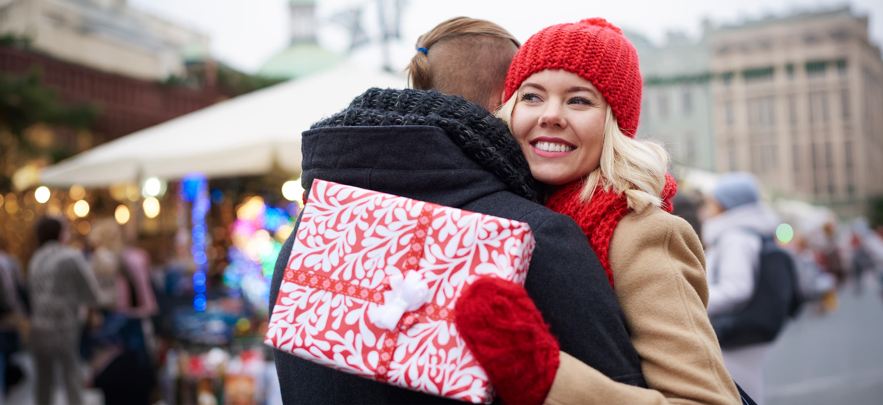 Couple hugging outdoors while holding a wrapped gift
