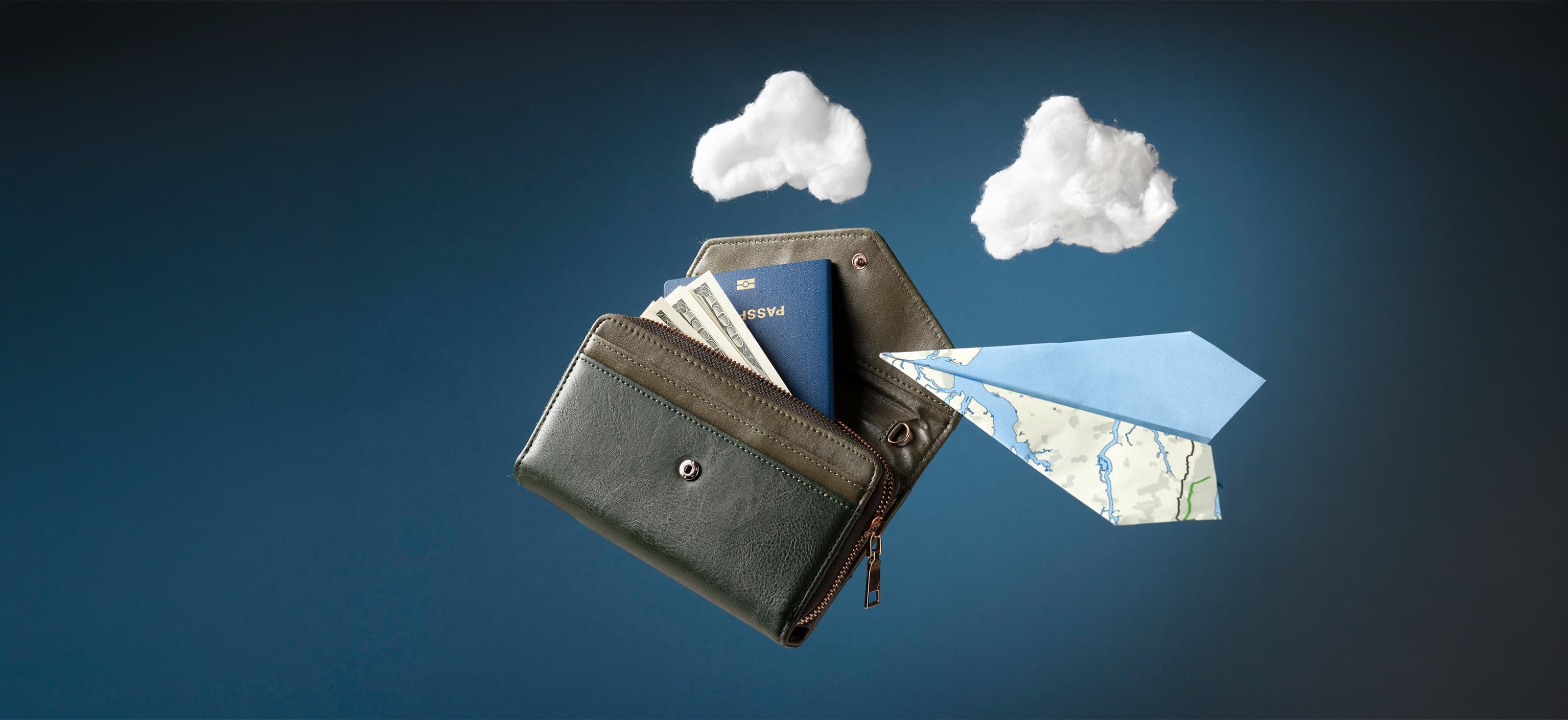 Travel wallet holding a passport and cash next to a paper-map airplane