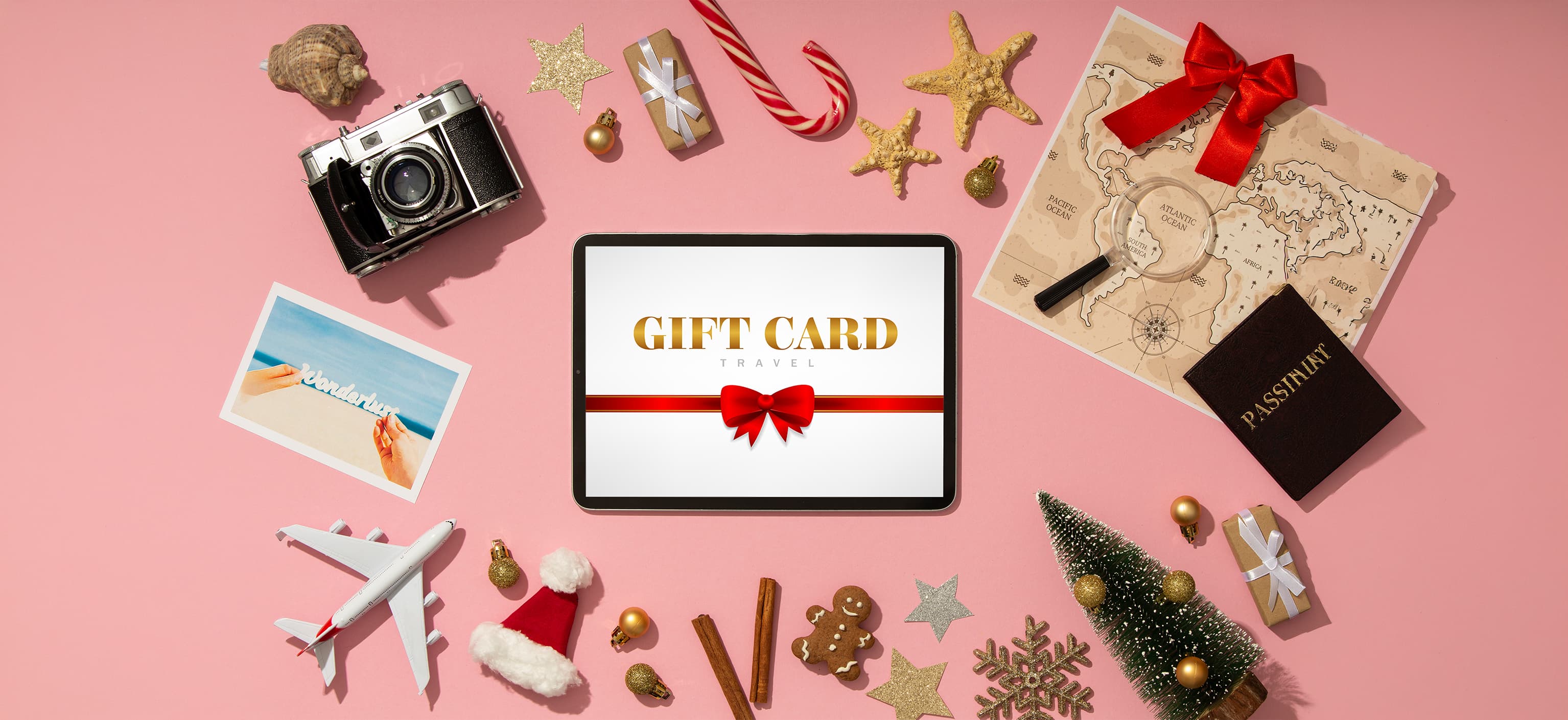 Tablet displaying a travel gift card surrounded by holiday and travel props