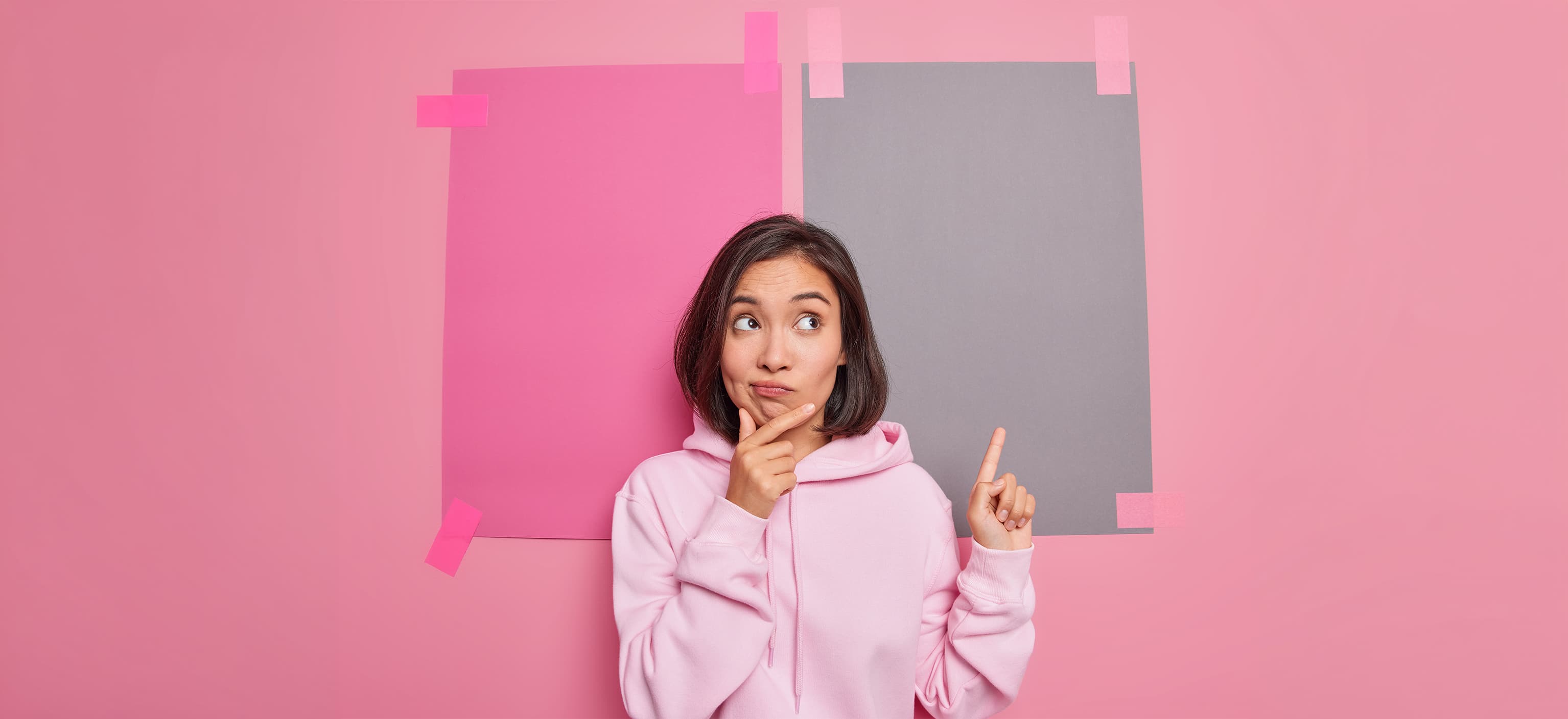 Woman thinking while pointing to one of two blank posters