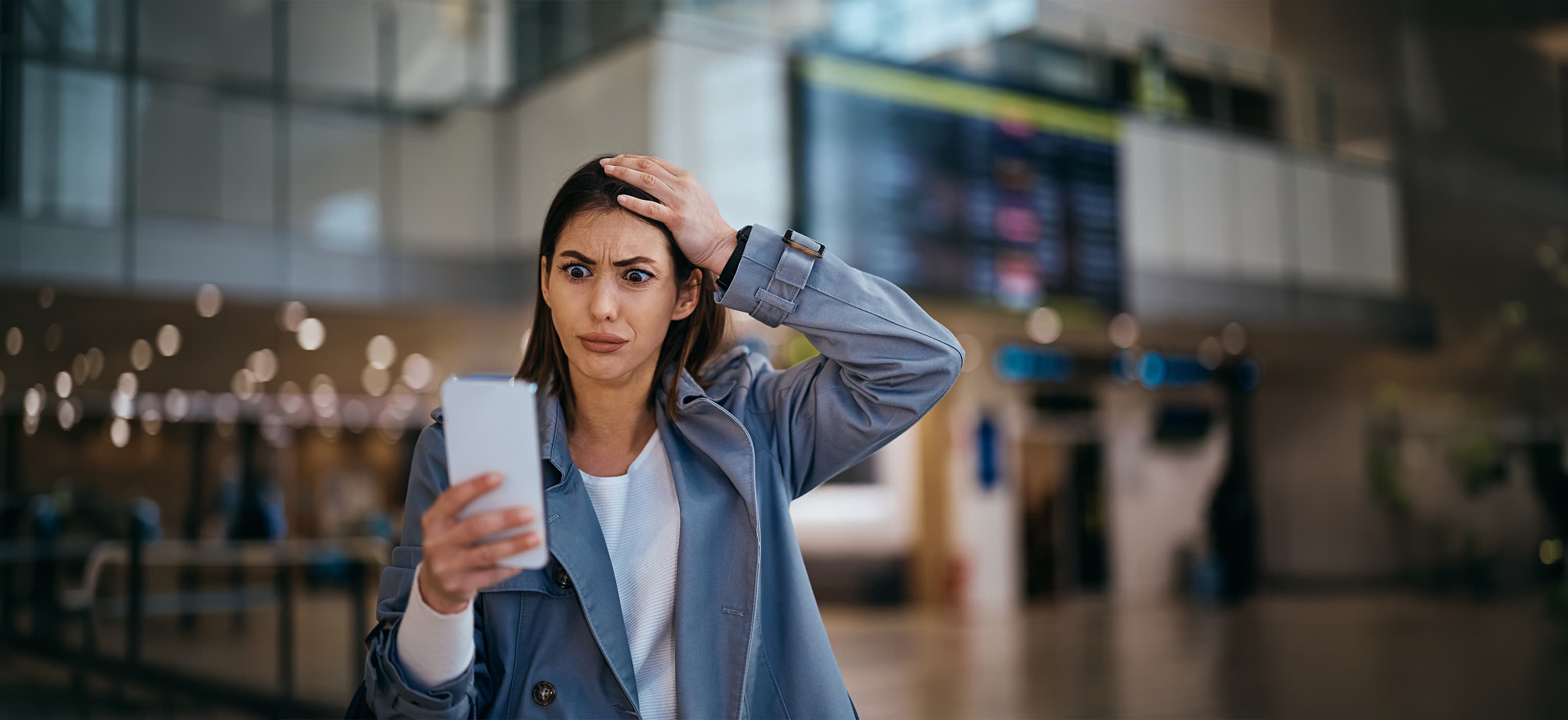 Surprised traveler staring at her phone screen in an airport